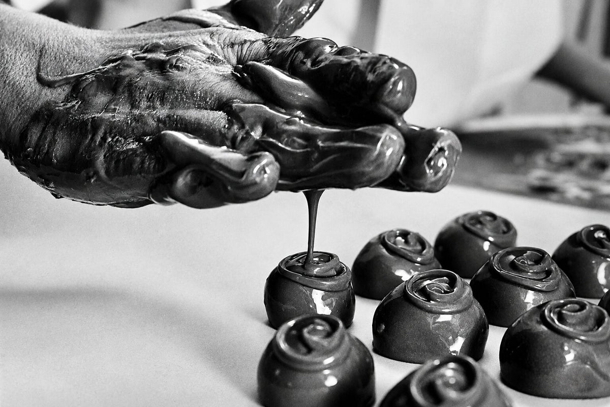 Chocolate maker hand-finishing pieces of chocolate at a workbench
